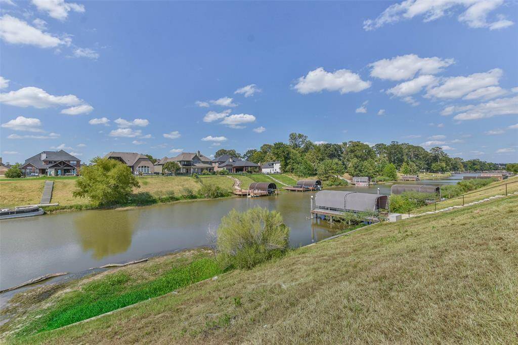 This photo showcases a serene waterfront community with spacious homes and manicured lawns. The neighborhood includes a picturesque canal access with a dock and a footbridge, offering a tranquil setting for outdoor activities and relaxation.