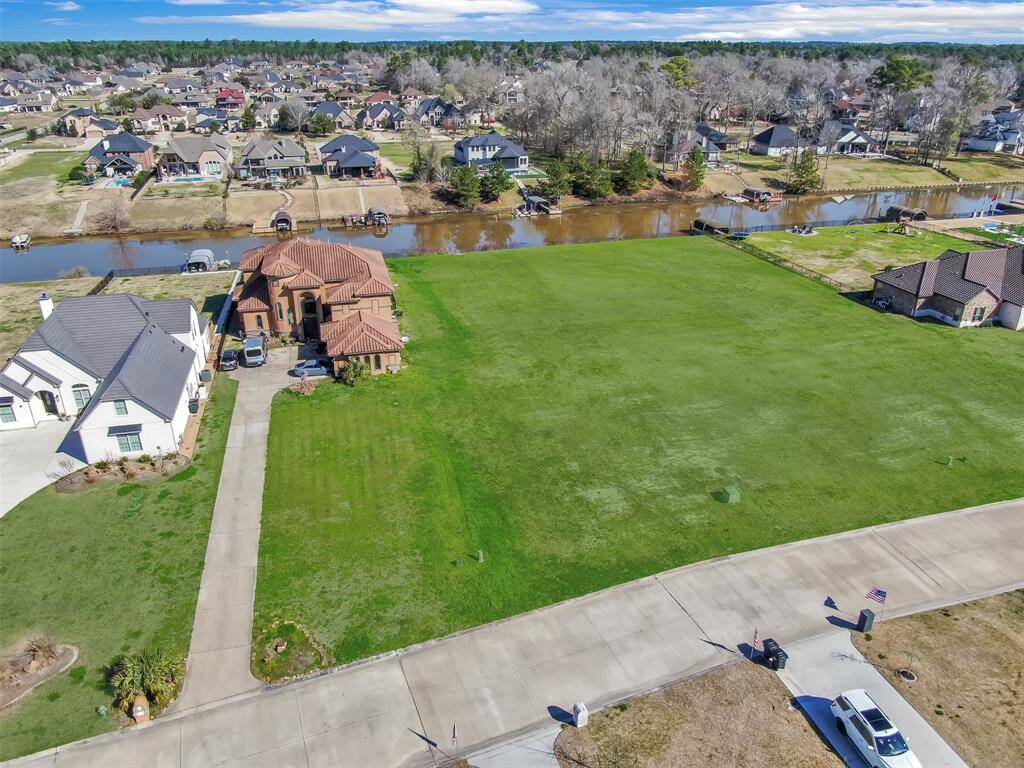 This aerial photograph showcases a spacious, vacant lot ready for development, adjacent to an attractive neighborhood with established homes. The lot is situated near a waterway, offering potential scenic views for a future residence.