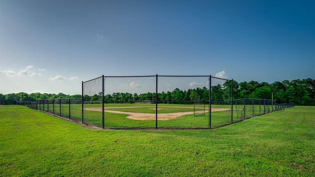 This is a well-maintained baseball field enclosed by a chain-link fence, set in a spacious, grassy area with clear skies above—ideal for sports enthusiasts and families seeking recreational amenities nearby.