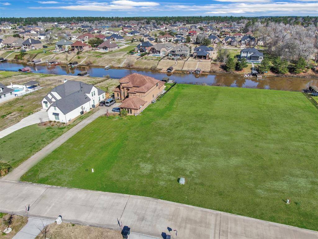 This aerial photo showcases a spacious, vacant lot ready for development, situated in a well-established neighborhood with a mix of architectural styles. The property backs onto a scenic water feature, offering potential for a home with water views and a degree of privacy.