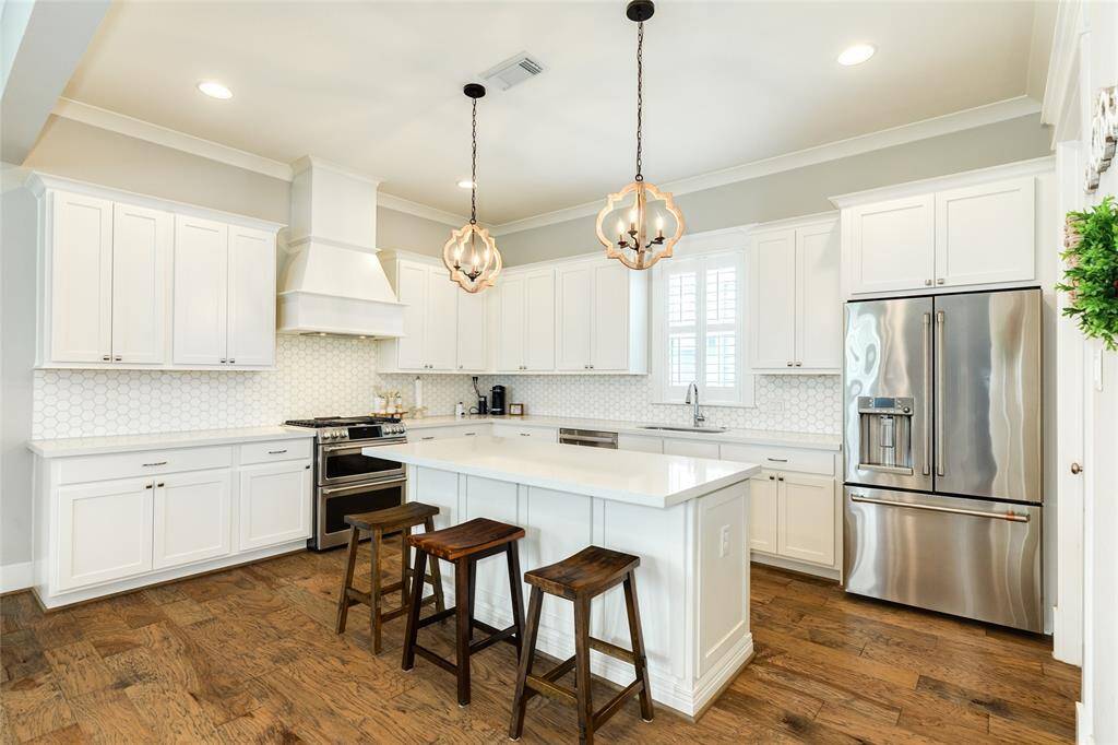 Tons of cabinets in this kitchen with quartz counters and decorative backsplash.