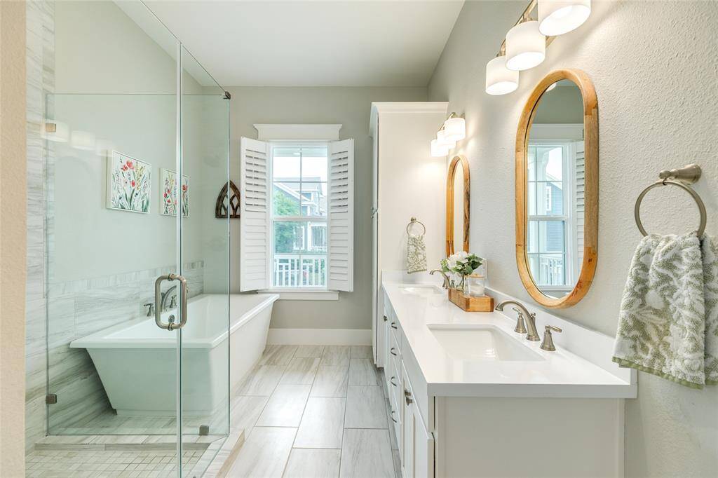 Soothing primary bath with soft colors, tiled floors, double vanity, walk in shower and soaking tub.