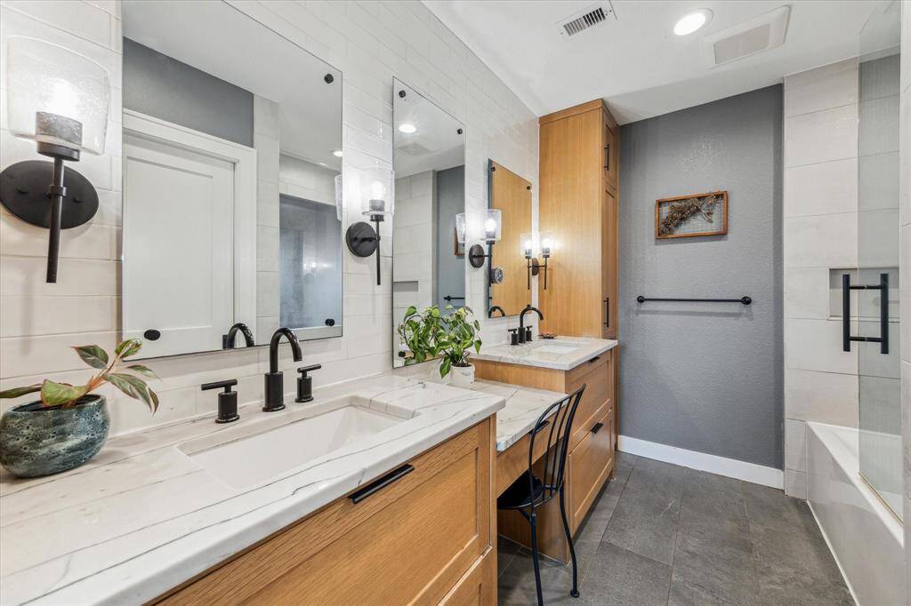A luxurious ensuite bath with quartzite counters, dual sinks, a makeup vanity, water closet and custom white oak cabinetry.