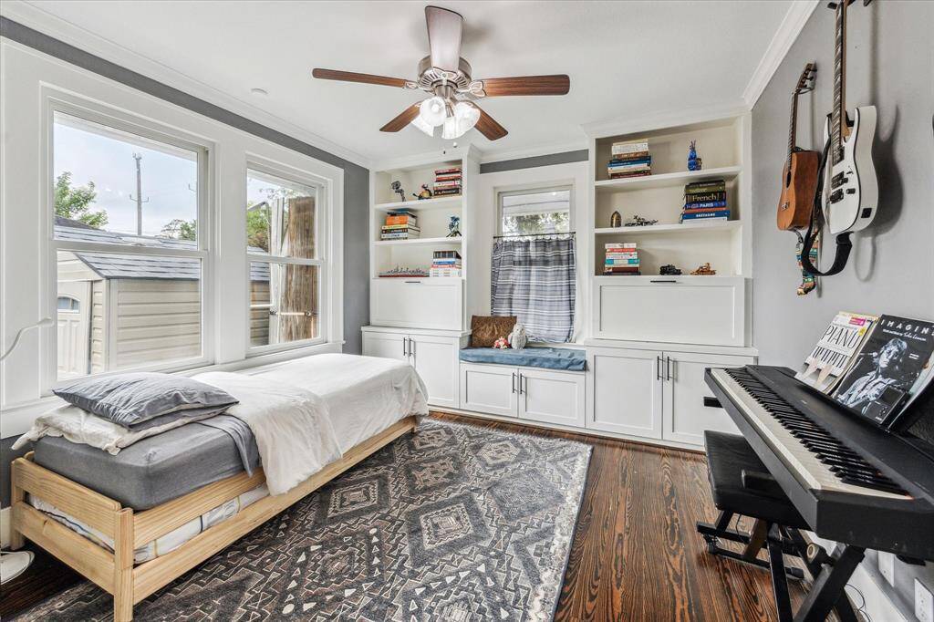 Secondary bedroom with hardwood floors, ceiling fan and custom built-in storage and secretary desk.
