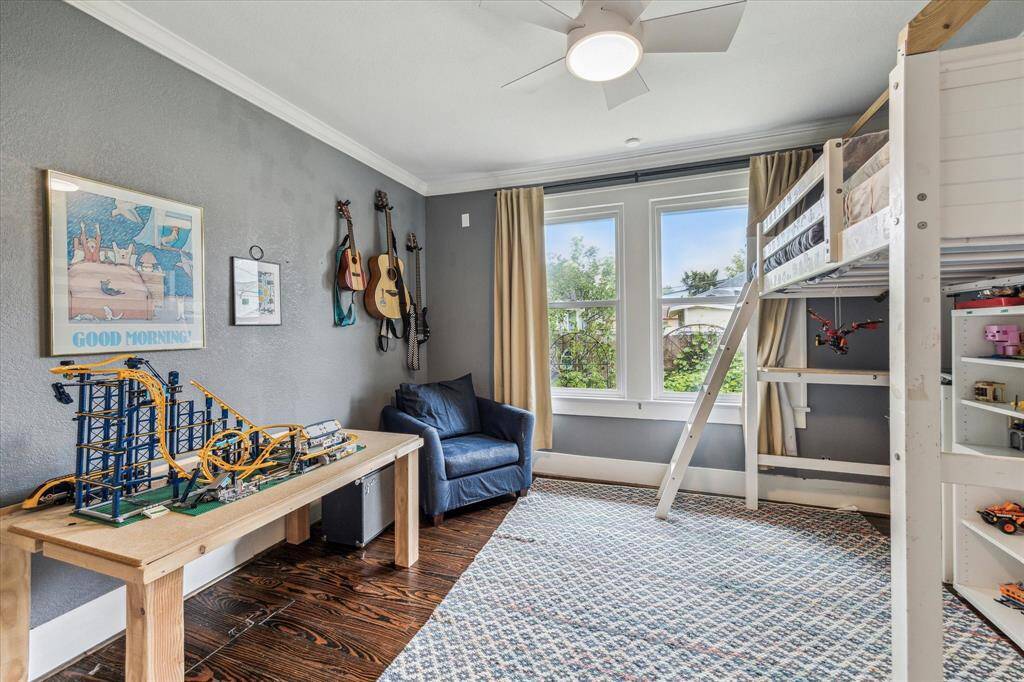 Secondary bedroom with hardwood floors, ceiling fan, custom built-in storage and views of the vegetable garden.