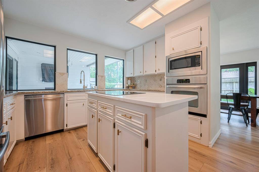 Stunning kitchen features quartz and granite countertops for a modern luxury appeal, stainless appliances, tumbled travertine backsplash and white cabinets.