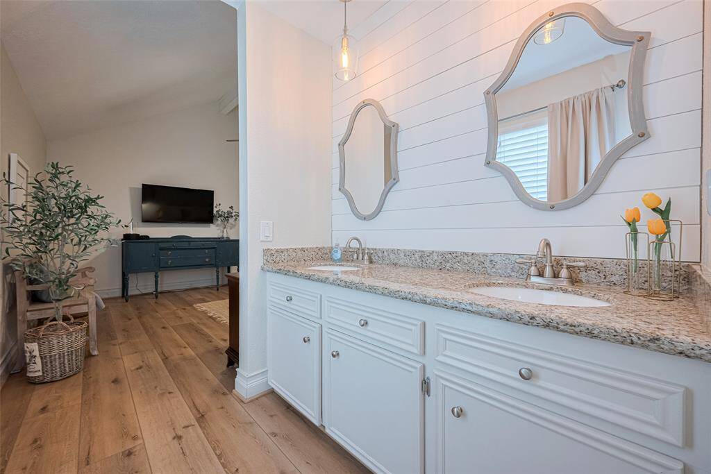 Primary bathroom offers dual sinks vanity, shiplap backsplash, modern hardware and plenty of light.