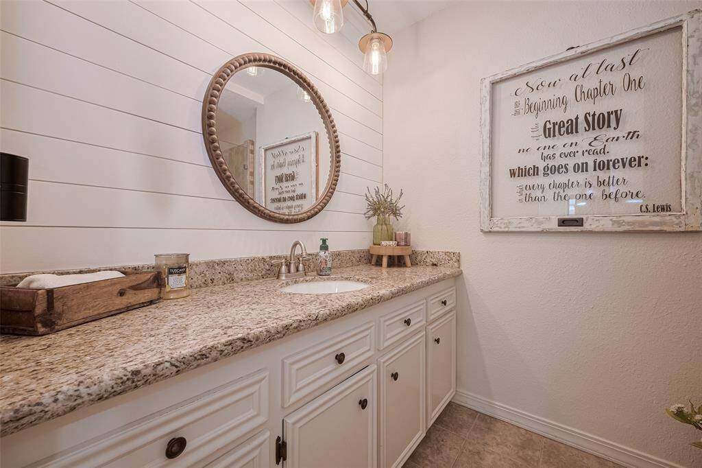 The second bathroom has been updated with granite countertop, modern fixtures, shiplap backsplash and fresh paint.