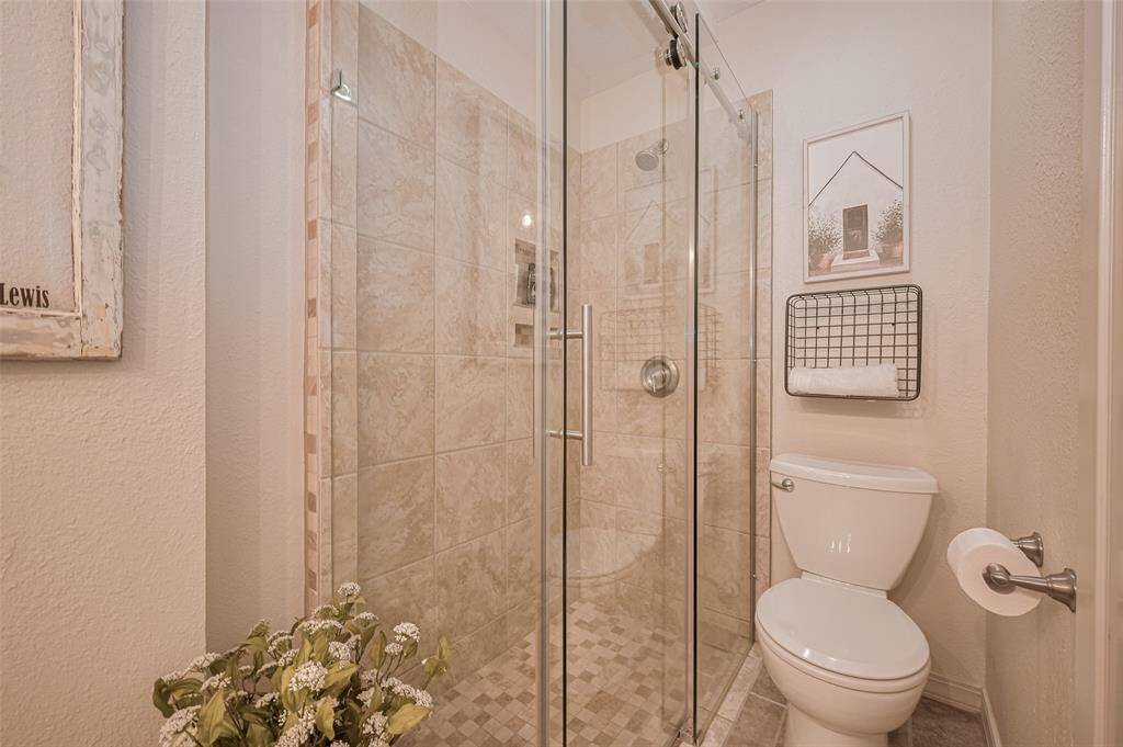 Second bathroom features a spacious shower with modern hardware, seamless glass and neutral tile.