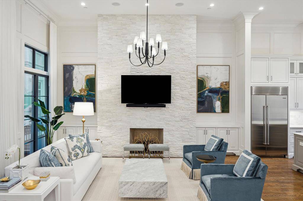 Anchored by a captivating fireplace as its central focal point, the living room is framed by exquisite French doors, offering a warm and inviting setting ideal for both intimate family gatherings and effortless everyday living.