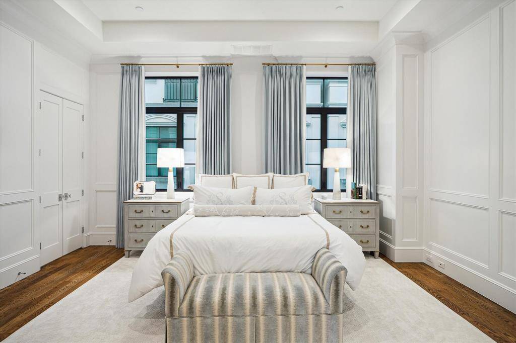 This primary suite at 1327 Peden features a spacious layout with high ceilings and elegant architectural details. Natural light streams through two large windows.
