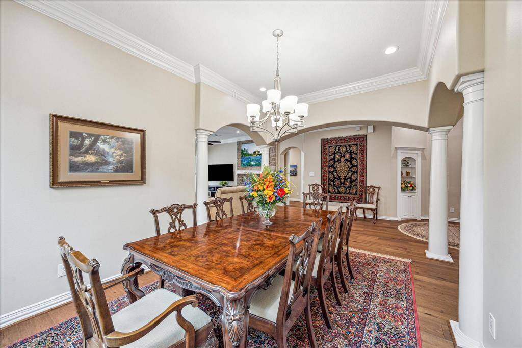 The dining room features elegant crown molding, recessed lighting, and a sophisticated chandelier, with an adjoining atrium that adds to the room's airy, open feel.