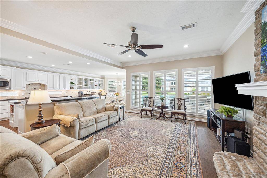 Seamlessly connected to the breakfast area and kitchen, the living room offers continued lake views, complemented by crown molding and a ceiling fan, creating a comfortable and inviting space.