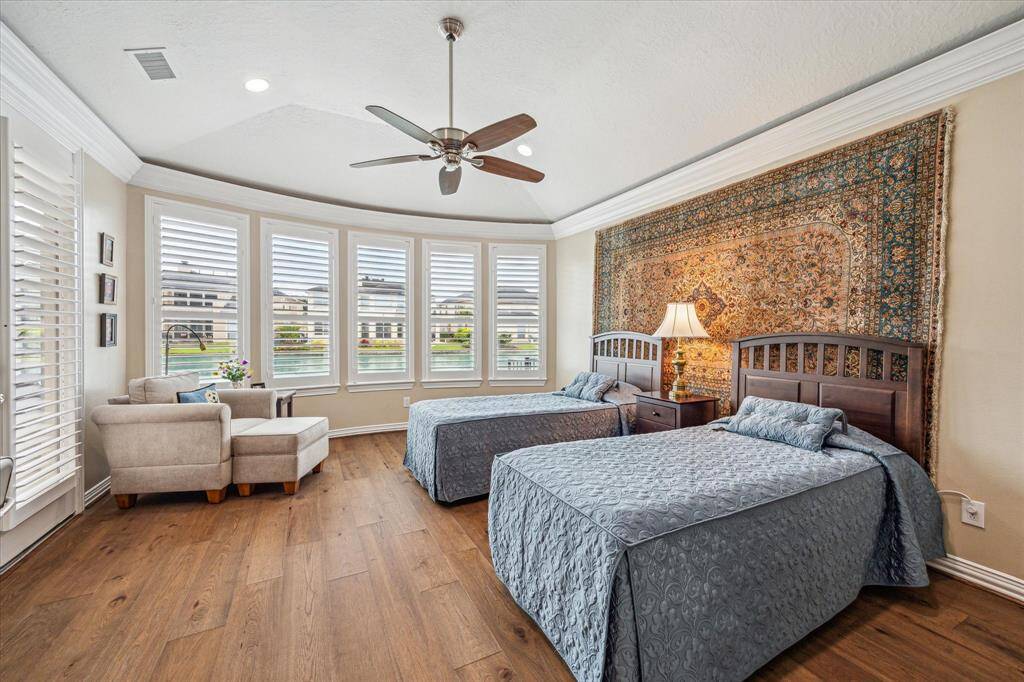 Here’s another view of the primary bedroom, featuring tranquil lake views, a vaulted ceiling, recessed lighting, and a ceiling fan for added comfort and style.