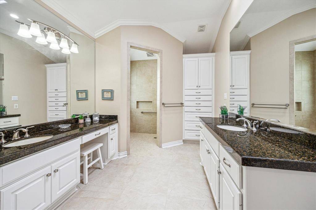 The expansive primary bath features dual sink vanities, a large walk-in shower, built-in cabinetry for added storage, and a spacious walk-in closet.