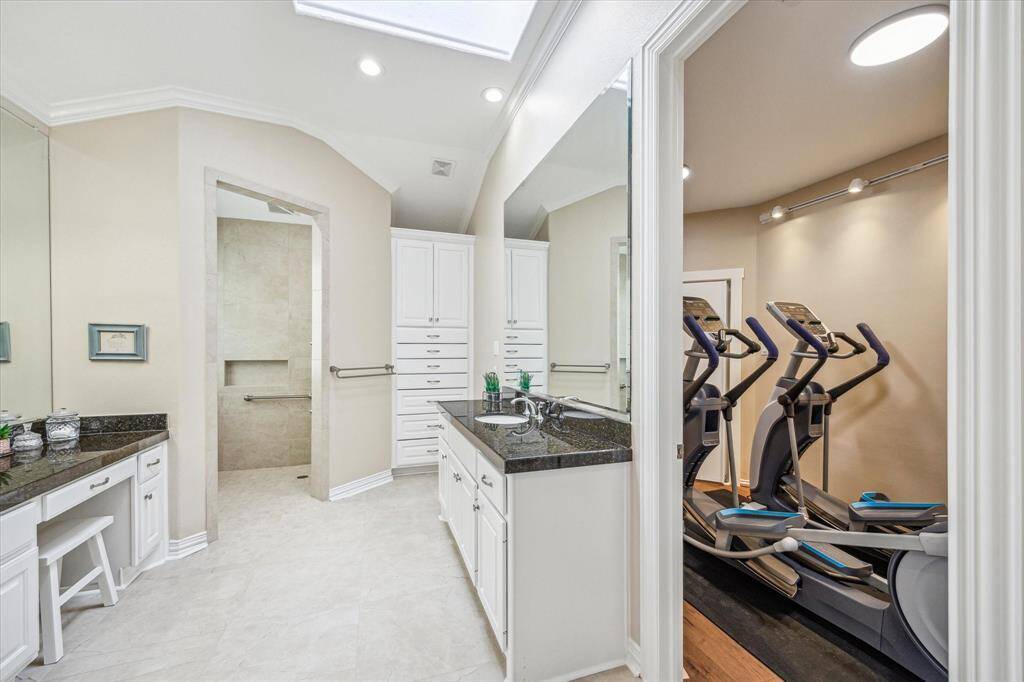 The primary bath also offers direct access to the flex room—a thoughtfully concealed space currently used as a home gym, adding versatility to the suite.