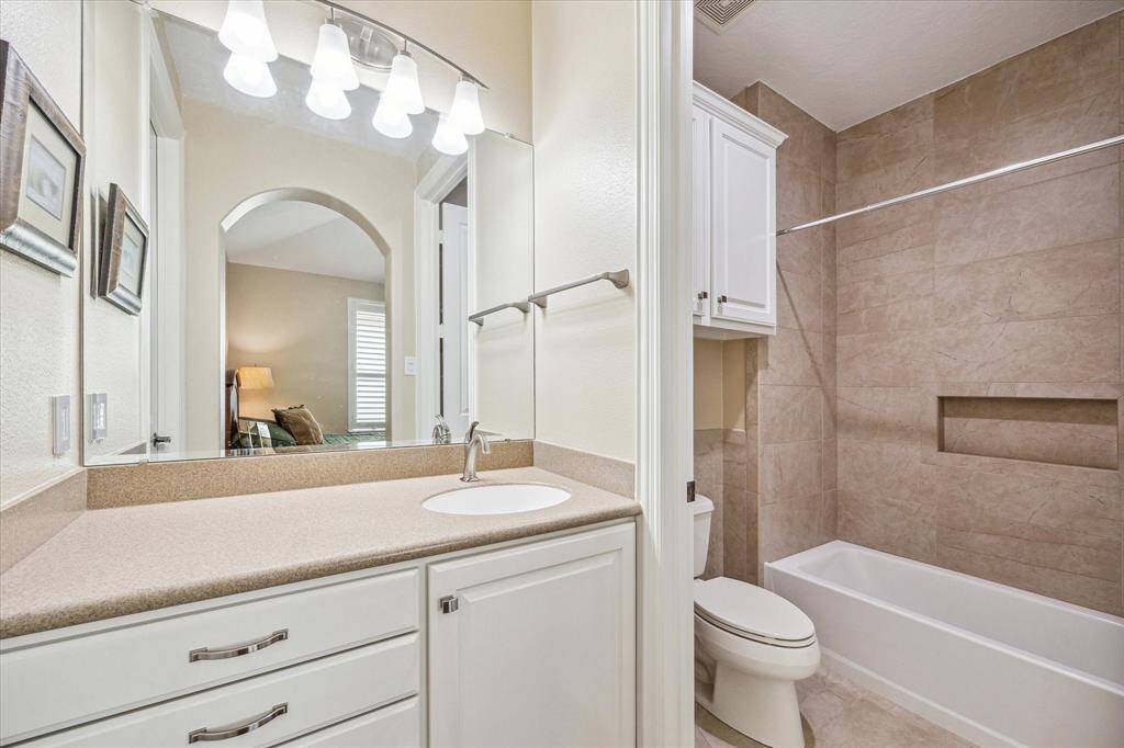 This secondary bath offers a tub-shower combination and is enhanced by bright, well-placed lighting.