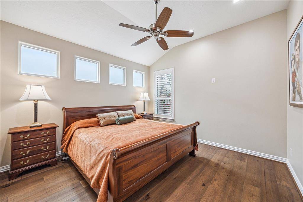 The secondary bedroom features a row of windows, recessed lighting, a ceiling fan, and an en-suite bath, creating a bright and comfortable retreat.