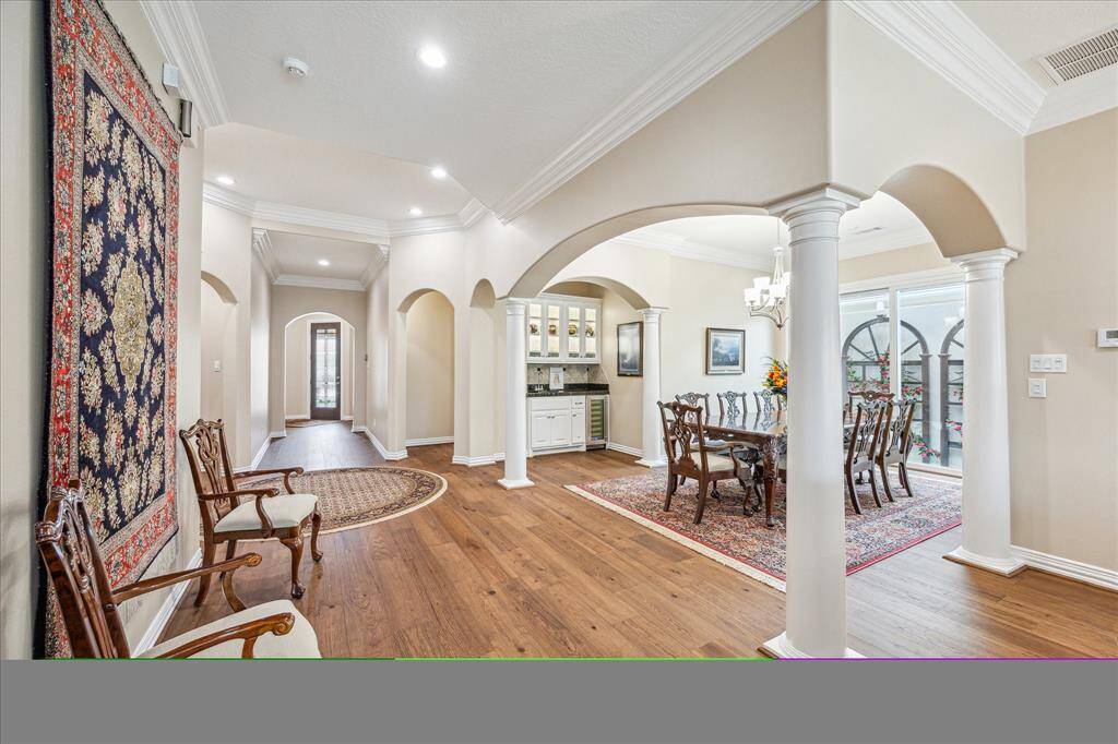 The dining room is centrally located and features elegant arched entryways with classic column-style detailing, adding a touch of architectural sophistication to the heart of the home.