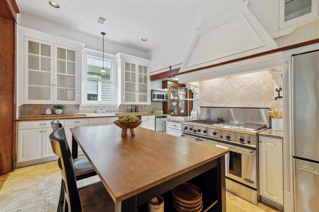 This spacious kitchen features glass-front cabinetry, a commercial-style range, and room to easily accommodate an island.
