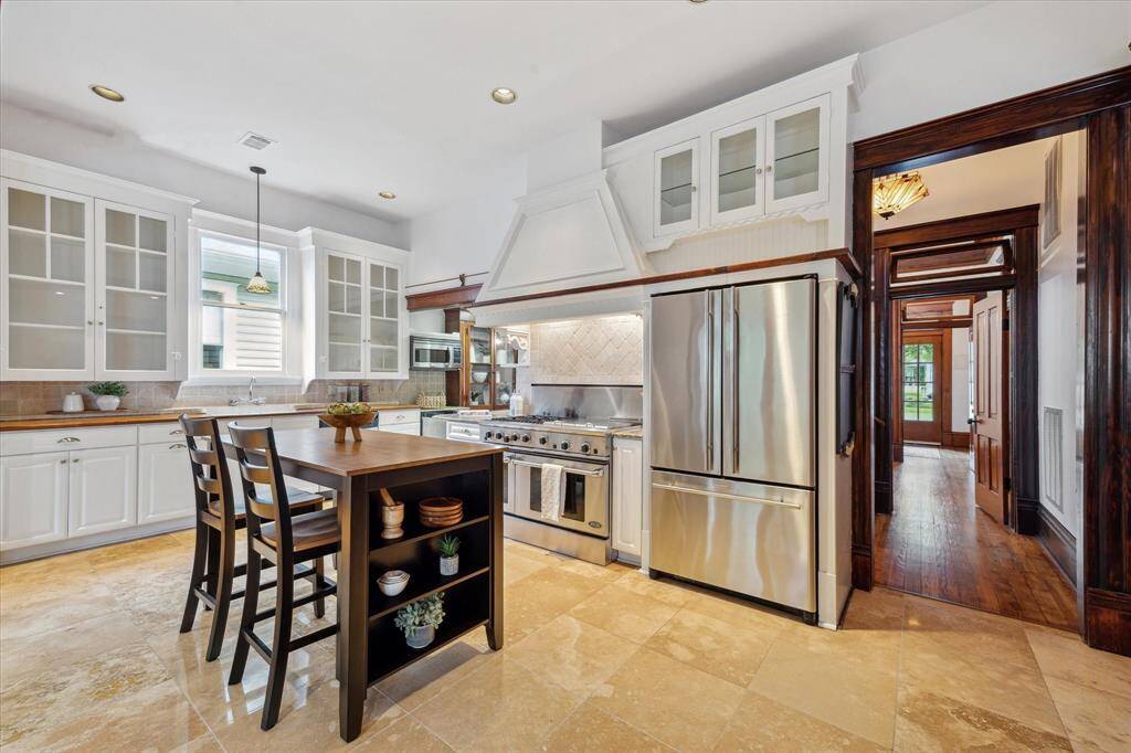 Stainless appliances and a striking vent hood elevate the kitchen - while the view down the hallway offers a warm glimpse of the home's flow and character.
