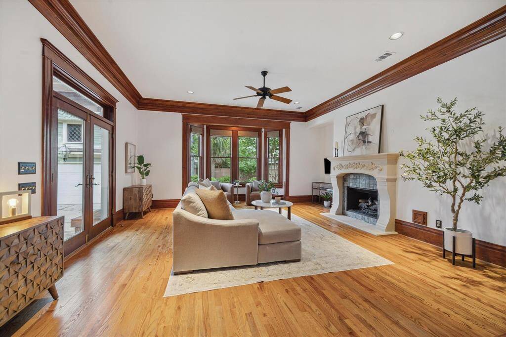 A stunning carved fireplace anchors the family room, offering an elegant focal point framed by tall windows and warm wood trim.