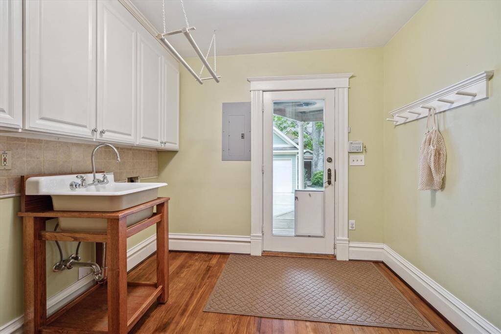Conveniently located just off the primary closet, this charming laundry room offers backyard access, ample cabinetry and a deep utility sink beneath a vintage style drying rack.
