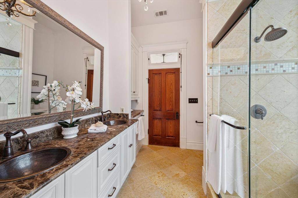 Anther view of the primary bath reveals elegant finishes and transom window avove the solid wood door.