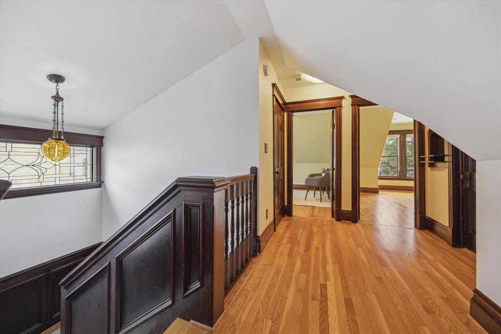 The paneled staircase leads to three upstairs bedrooms and is illuminated by a vintage light fixture and leaded glass window that fills the space with soft natural light.