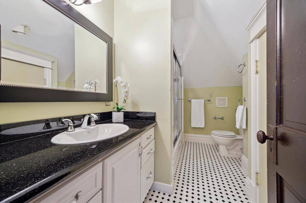 This upstairs bathroom, shared by all 3 bedroooms, features classic black and white tile flooring and a glass enclosed tub/shower combo.