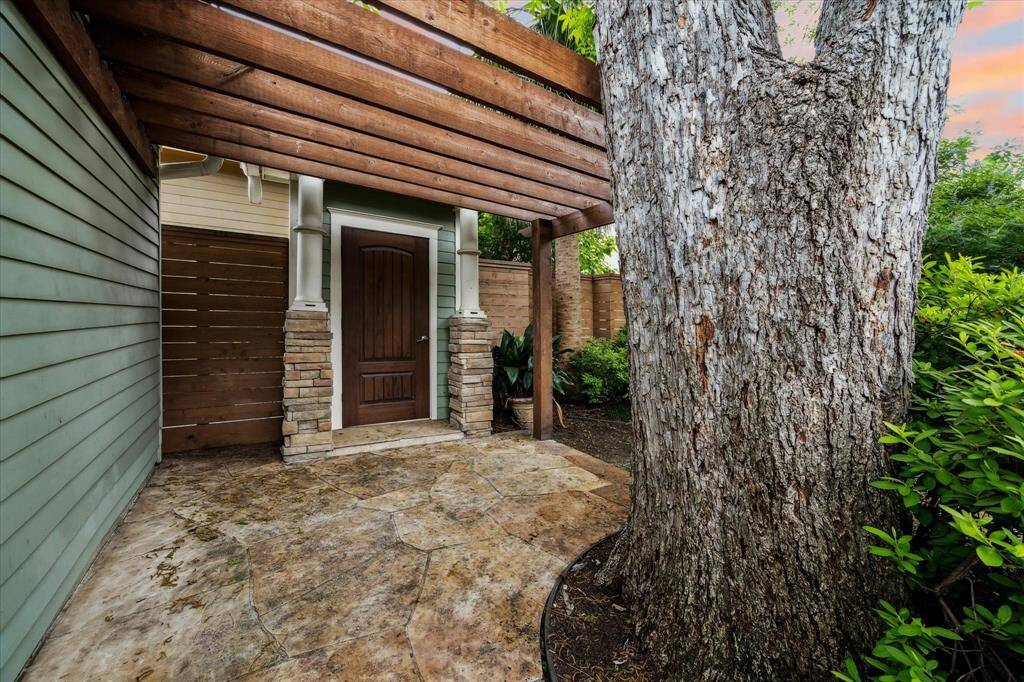 This covered side entrance, framed by stacked stone columns and rustic beams, offers private access to the alleyway.