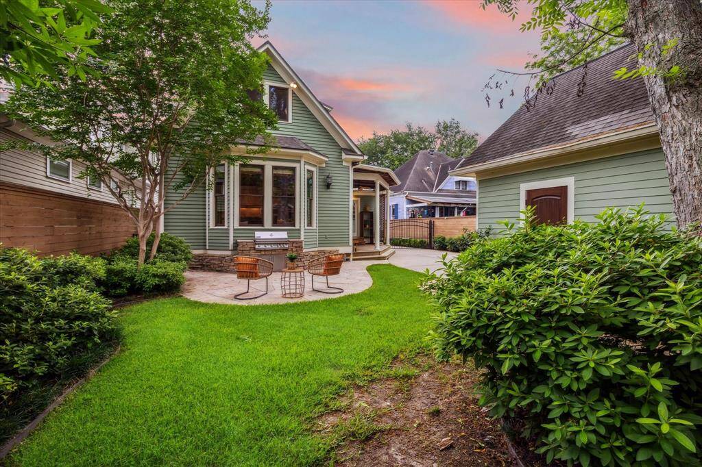 The backyard offers a seamless blend of lush lawn, stone patio area for lively gatherings or relaxed evenings. The Vitex tree to the left has the most beautiful lavender blooms!
