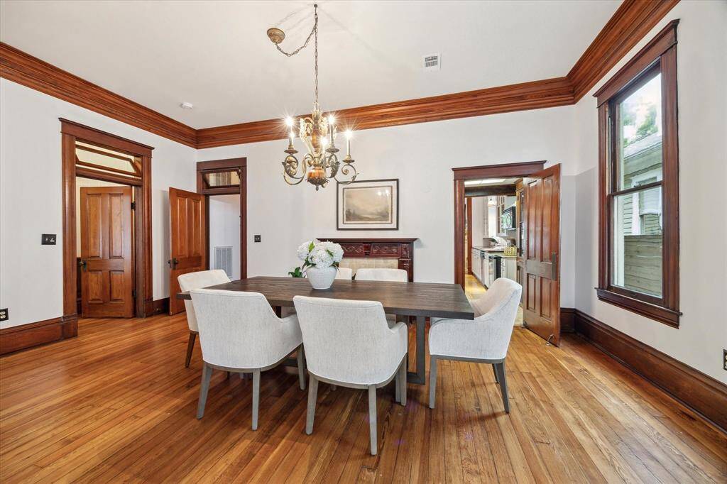 Warm wood trim and transom windows highlight the architectural charm as the dining room opens gracefully to the kitchen.