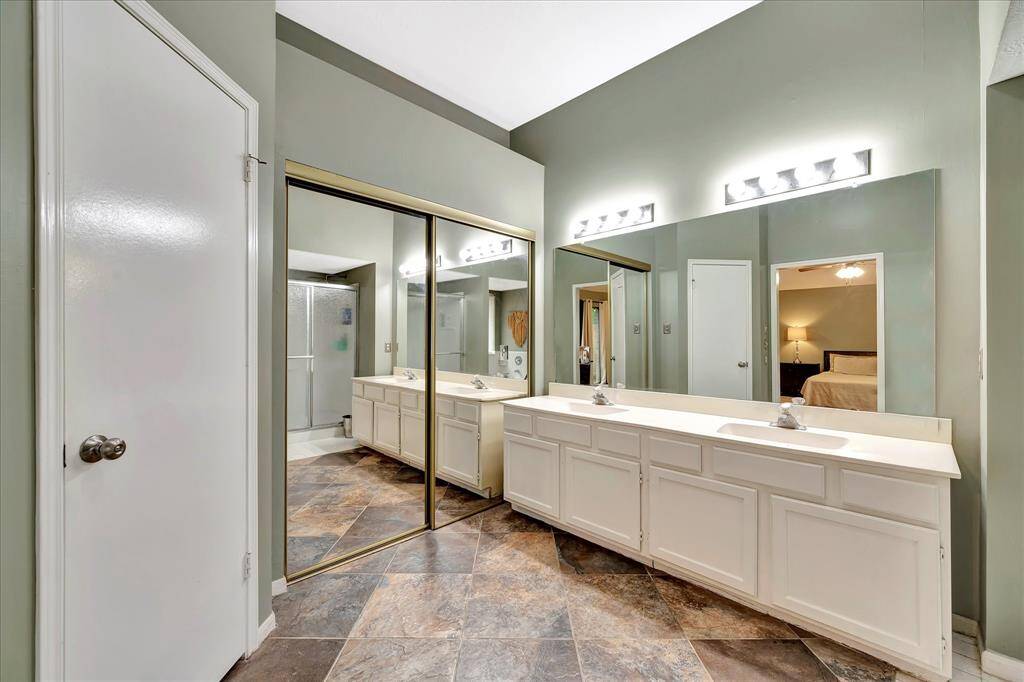 Primary bathroom with double sinks. Mirrored sliding doors lead to walk-in closet.