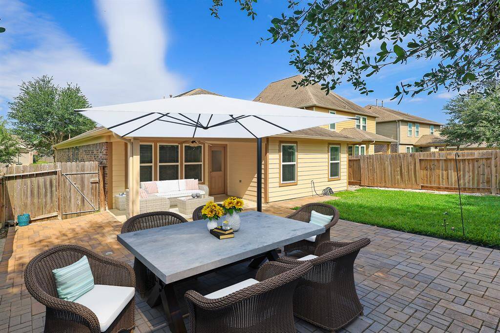 Enjoy outdoor living with a covered patio, stylish pavers, and lush green space. Fabulous for family events outdoors! Virtually Staged for inspiration.