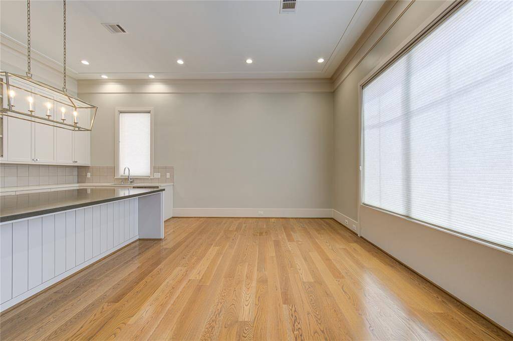 Bright, open-concept kitchen and dining area with hardwood floors, modern lighting, large windows, and sleek cabinetry. Ideal for entertaining and family gatherings.
