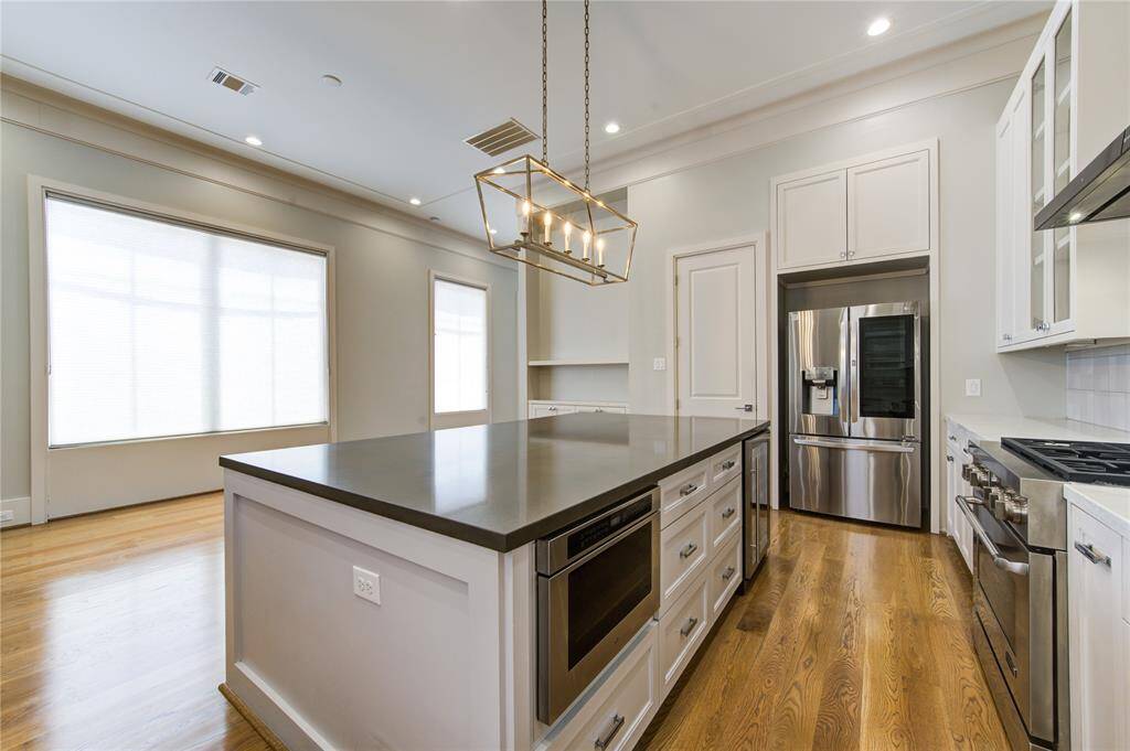 Bright and spacious kitchen with modern stainless steel appliances, a large center island, hardwood floors, and ample natural light. Perfect for cooking enthusiasts and entertaining.