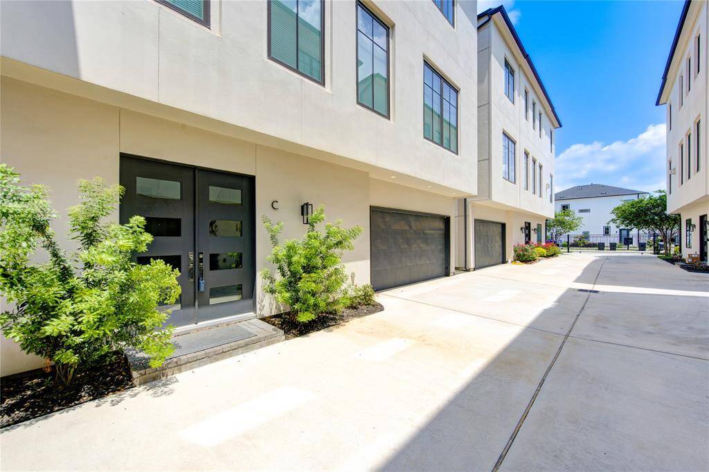 This photo showcases a modern townhouse complex with clean lines and a light facade. The area features a paved driveway, garage, and minimal landscaping, offering a sleek and low-maintenance living environment.
