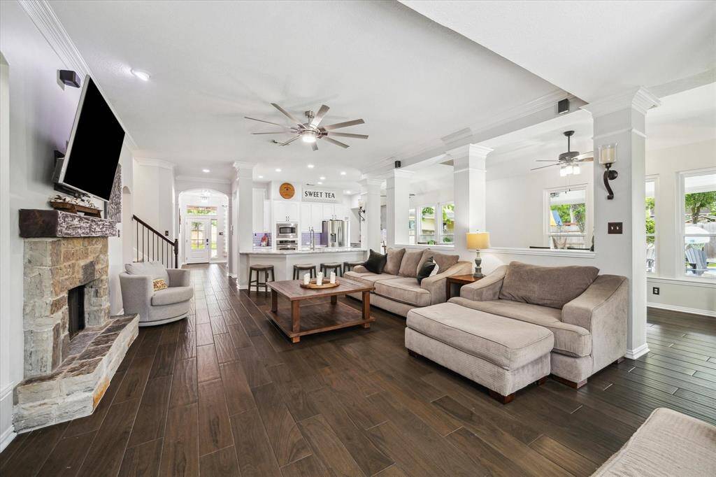 OPEN-CONCEPT FAMILY ROOM WITH UPDATED STONE FIREPLACE, NEW WINDOWS (2024), AND GLEAMING WOOD-LOOK TILE THROUGHOUT.