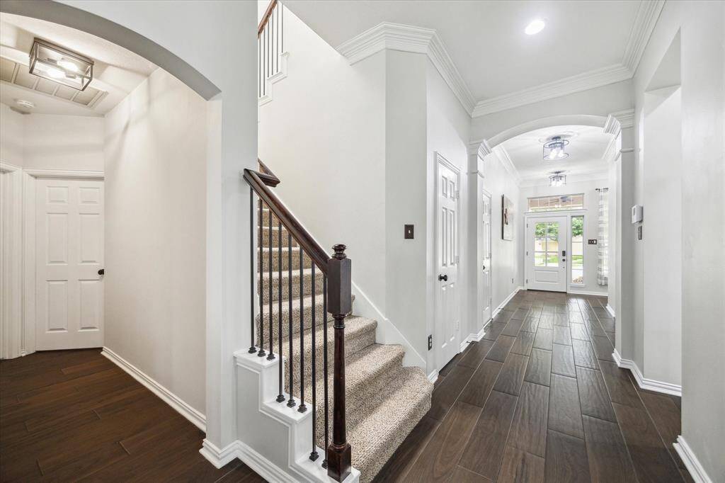 ENTRY HALL FEATURING A WROUGHT IRON STAIRCASE AND VIEWS TOWARD THE FRONT DOOR THAT FRAME THE HOME’S ELEGANCE FROM EVERY ANGLE.
