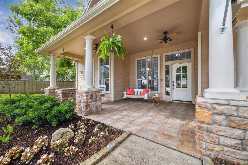 LARGE COVERED FRONT PORCH WITH TILE FLOORING, CEILING FANS, AND SWING SEATING—A PERFECT SPOT TO ENJOY THE TREE-LINED STREET IN THIS HIGHLY DESIRABLE COMMUNITY.
