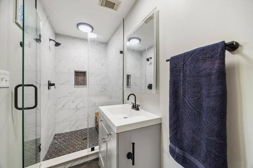 UPDATED BATH WITH WALK-IN SHOWER, MODERN VANITY, AND DESIGNER TILE.