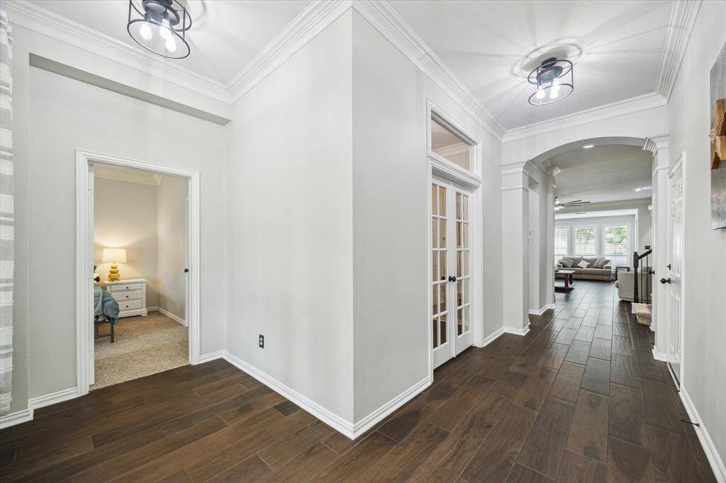 ELEGANT ENTRYWAY WITH WOOD-LOOK TILE FLOORING, CROWN MOLDING, AND DOUBLE FRENCH DOORS TO A PRIVATE STUDY.