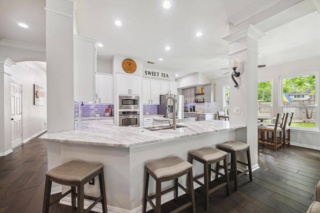 STUNNING CHEF'S KITCHEN WITH EXPANSIVE MARBLE COUNTERS & BAR SEATING.