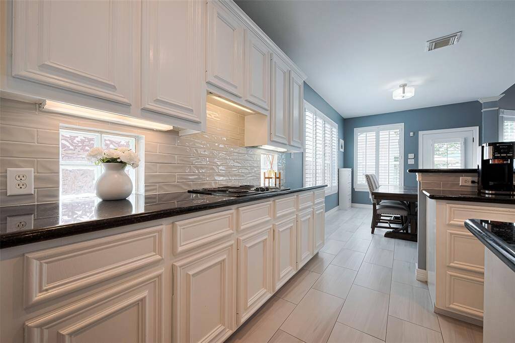 The kitchen offers white subway tile backsplash, granite counters and and abundance of cabinet storage.