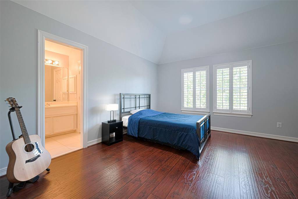 Bedroom #2 upstairs features easy to maintain rich wood-look laminate floors, high ceilings, shutters and it's own vanity and sink.