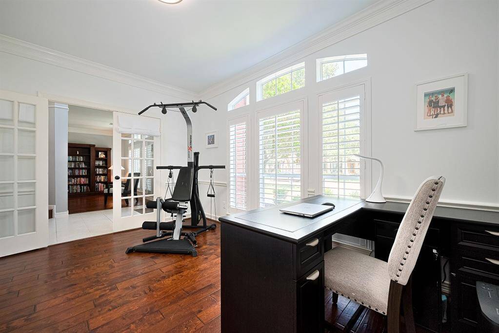 The office features wood floors, french doors & shutters on the windows