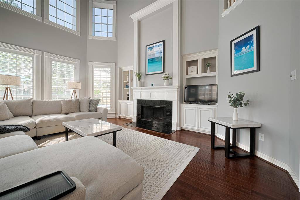 The living room offers soaring ceilings, rich wood floors, shutters, crown molding, shutters, and modern finishes.