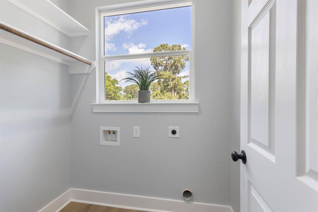 The utility room offers a cute window and shelving making laundry days more enjoyable.
