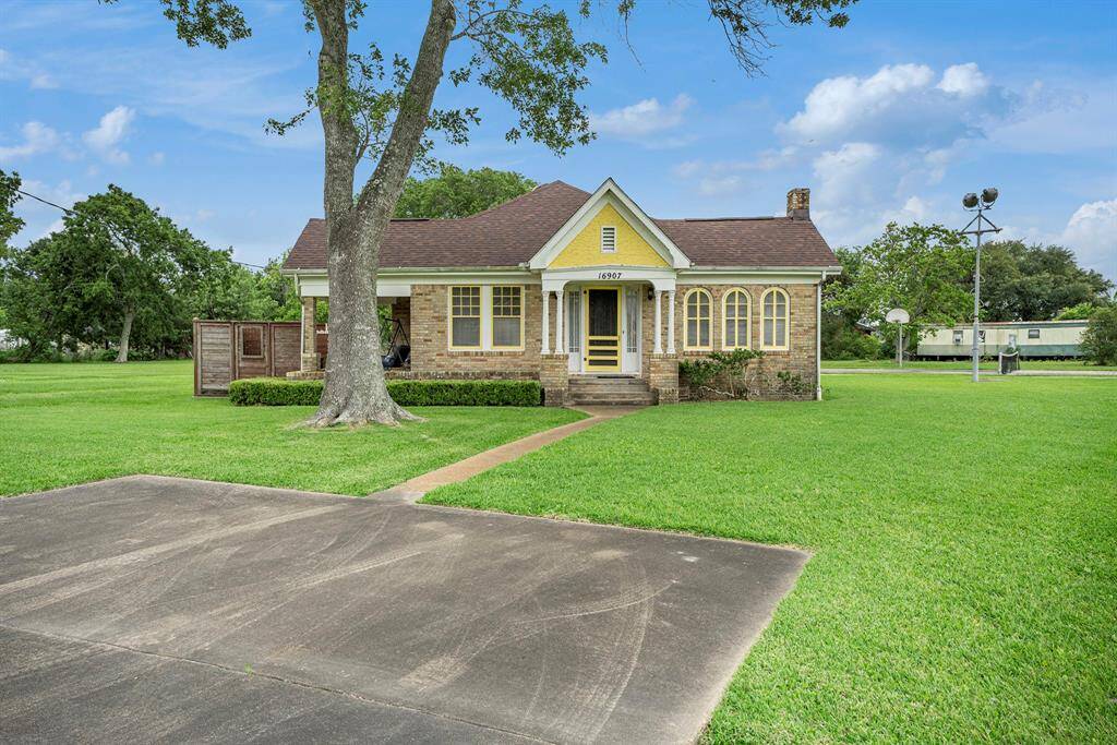 Charming single-story brick home with a welcoming front porch, situated on a spacious, well-maintained lawn. Features a long driveway and mature trees, providing a serene, open setting ideal for family living.